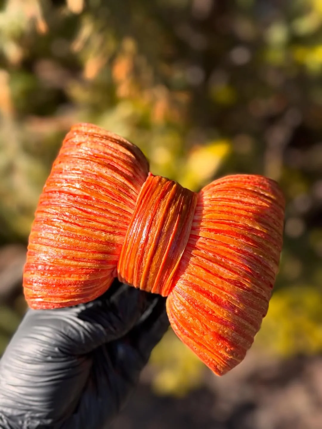 Le Nœud — laminated bow croissant tinted with beetroot and turmeric, brushed with apricot glaze